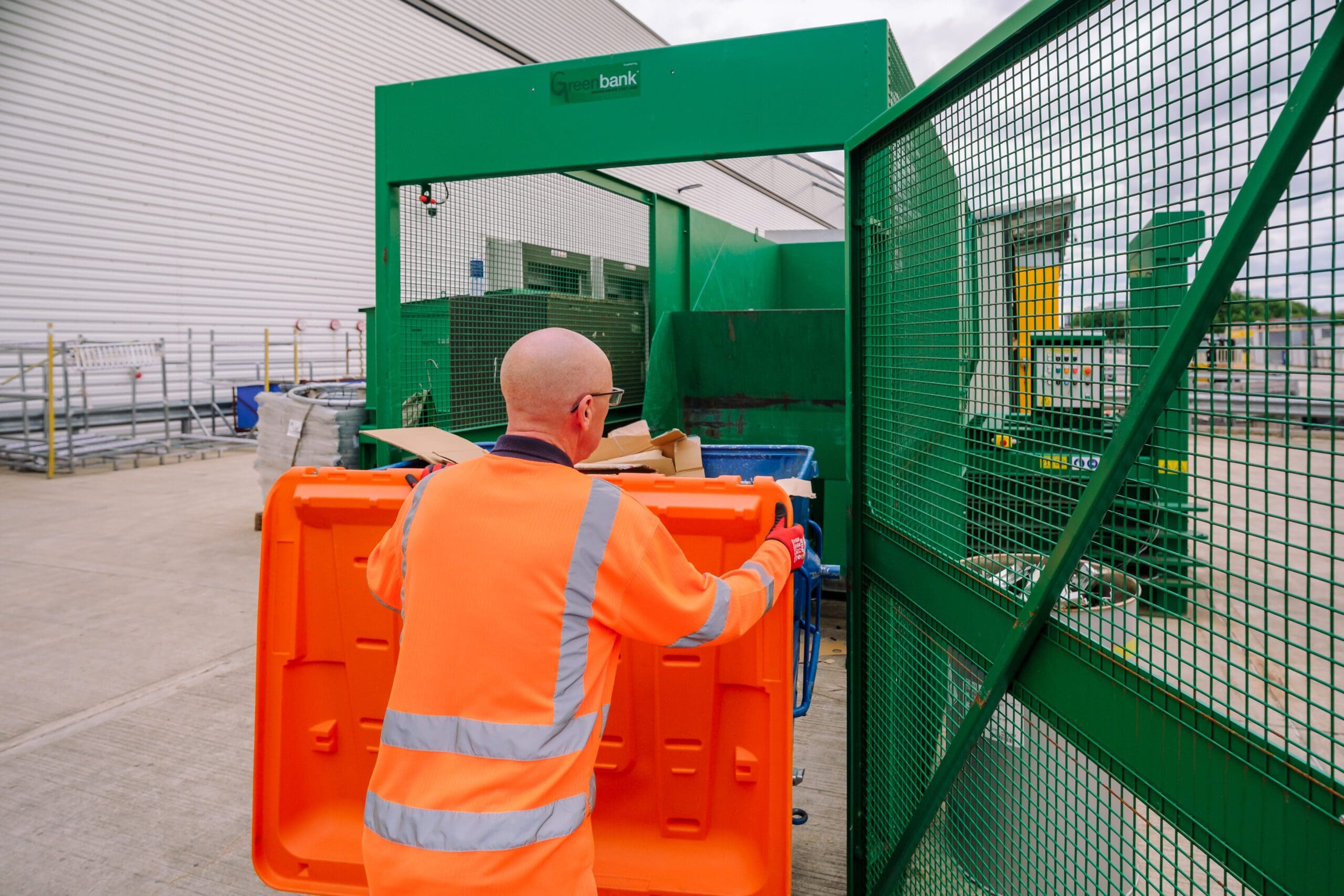 Axil employee loading cardboard bin into Cardboard Baler