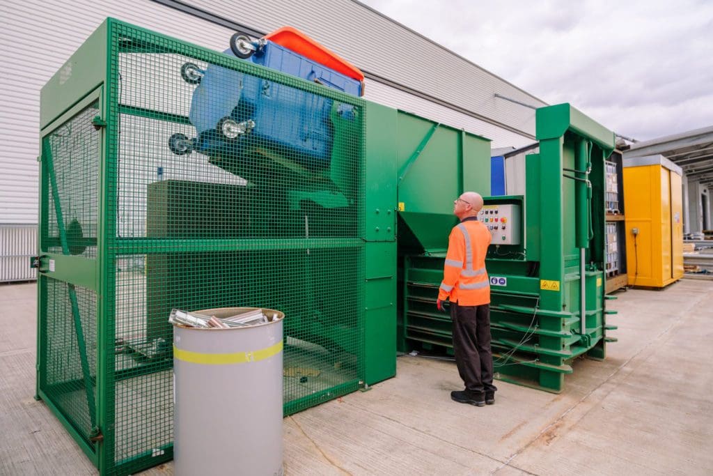 Axil employee, Bin loaded into Cardboard Baler