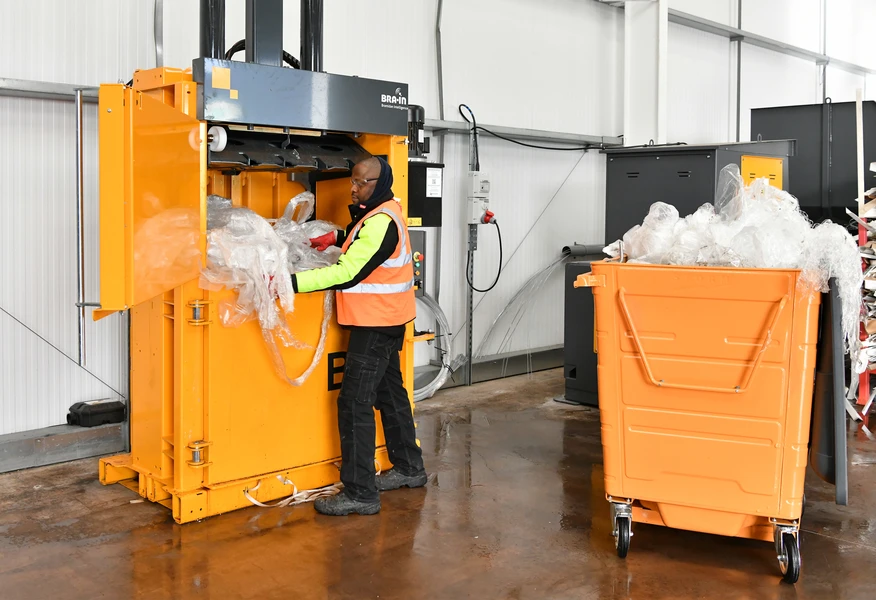 Axil operative processing plastic film through a baler at a resource recovery facility, supporting efficient recycling and sustainable waste management solutions.